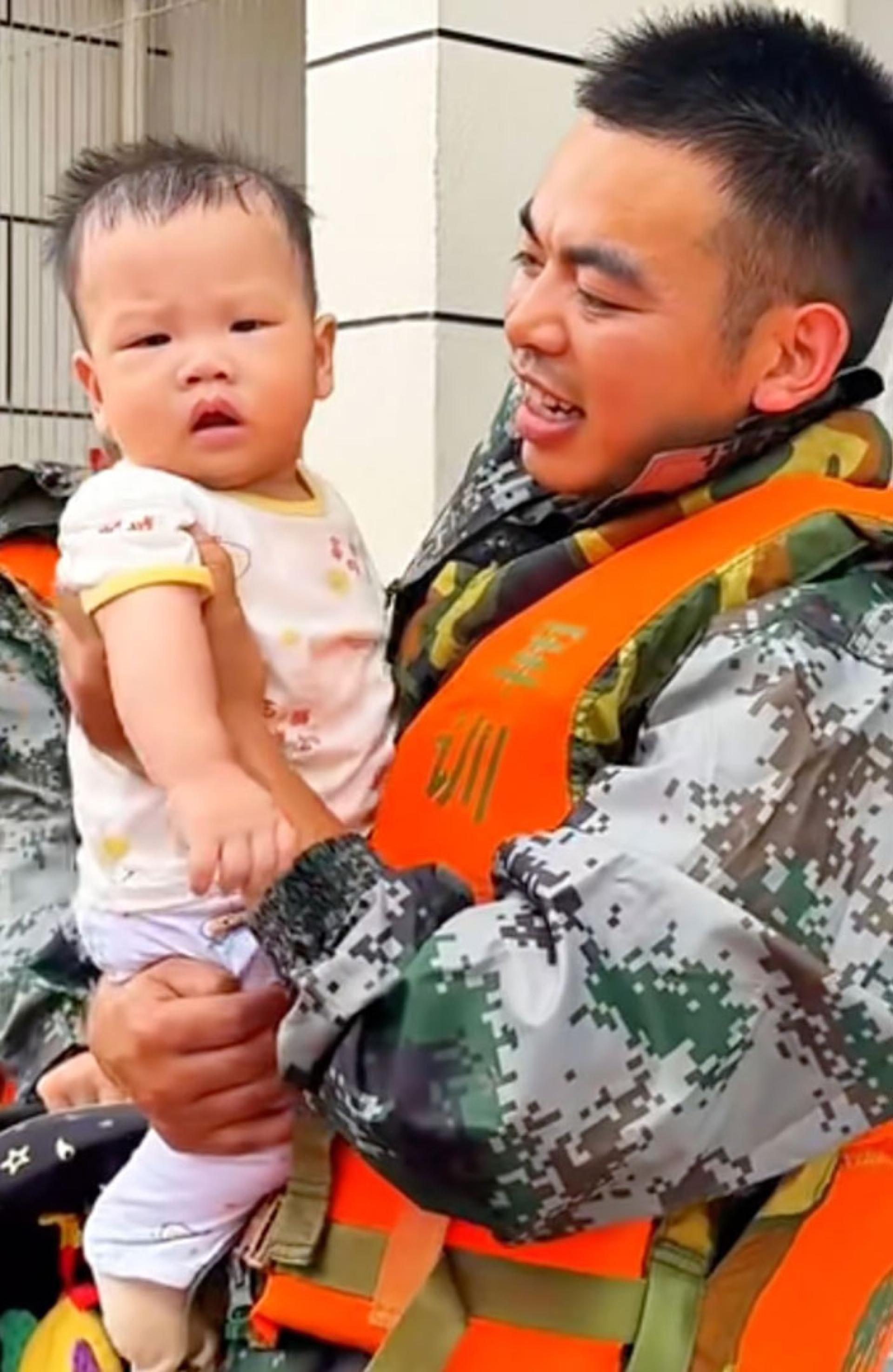 吴杰抱着从受灾区救出的婴儿。