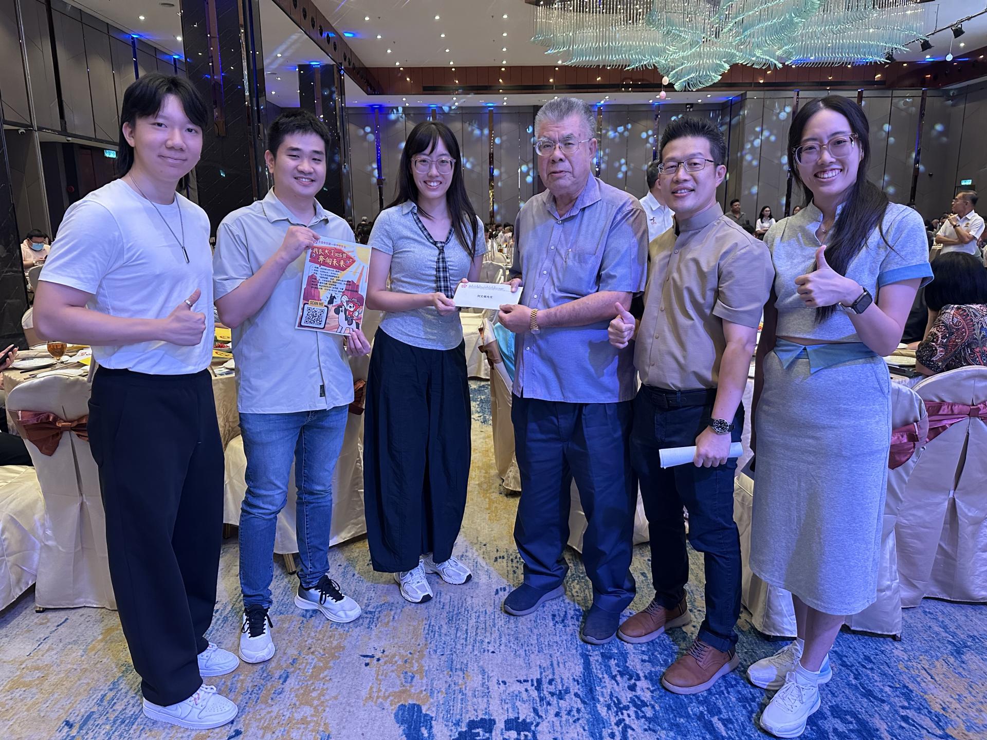 筹委会主席锺汶璇（左3）与古晋中华第一中学校友会会长李嘉浩（右2）及理事们一行人，移交小六欢乐营邀请函予名誉顾问刘文侯校友（右3）。