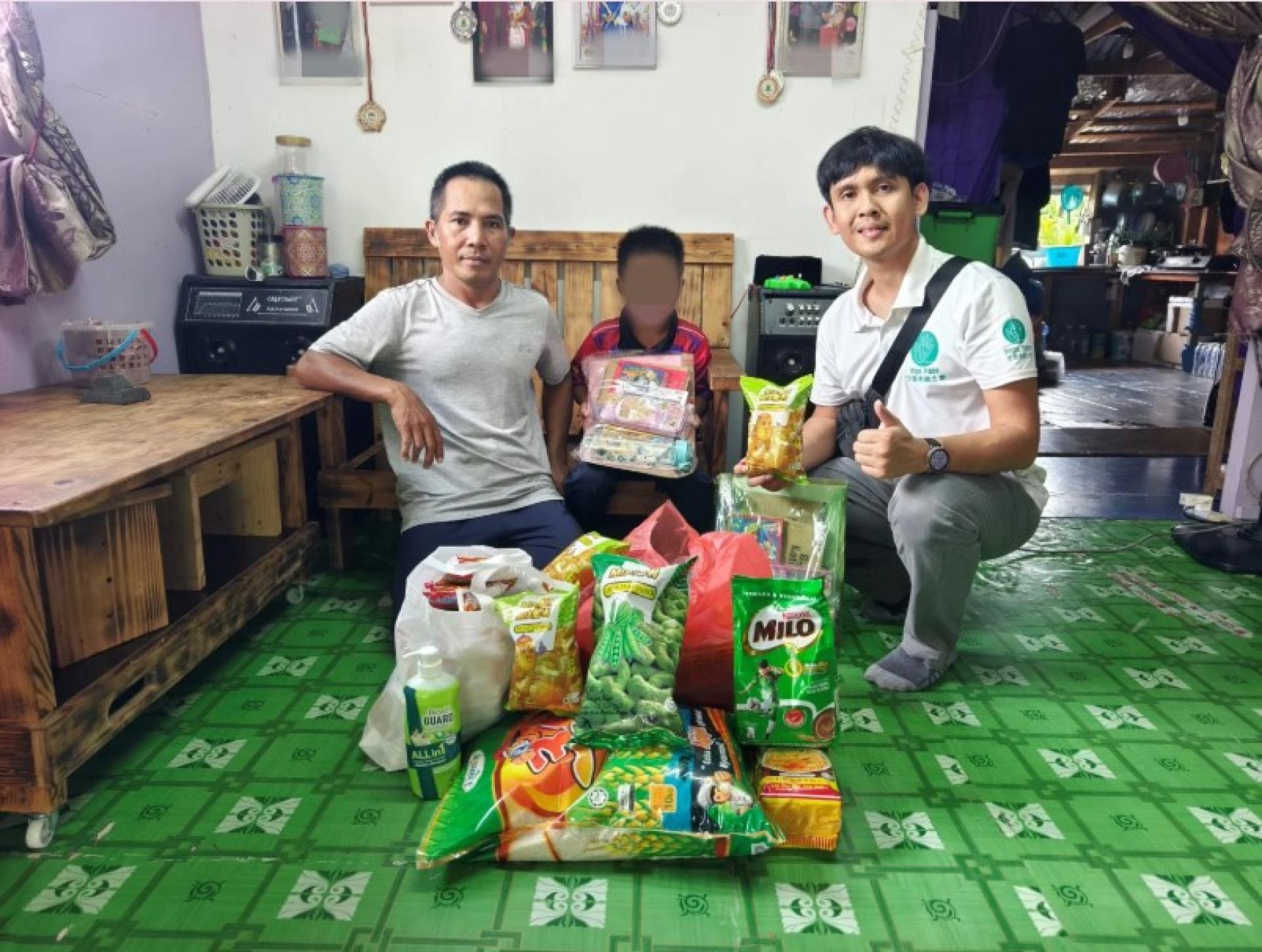卡马鲁丁·卡欣（左）与儿子（中）领取由希望之家代表Griffin Deng，（右）移交的粮食援助。