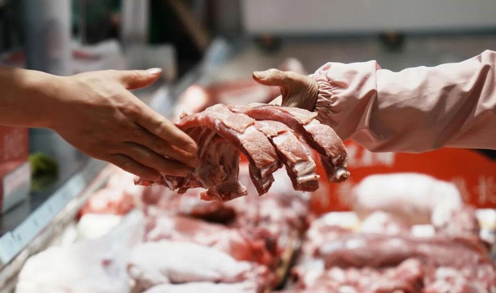 图为5月11日，顾客在杭州一家超市选购猪肉。