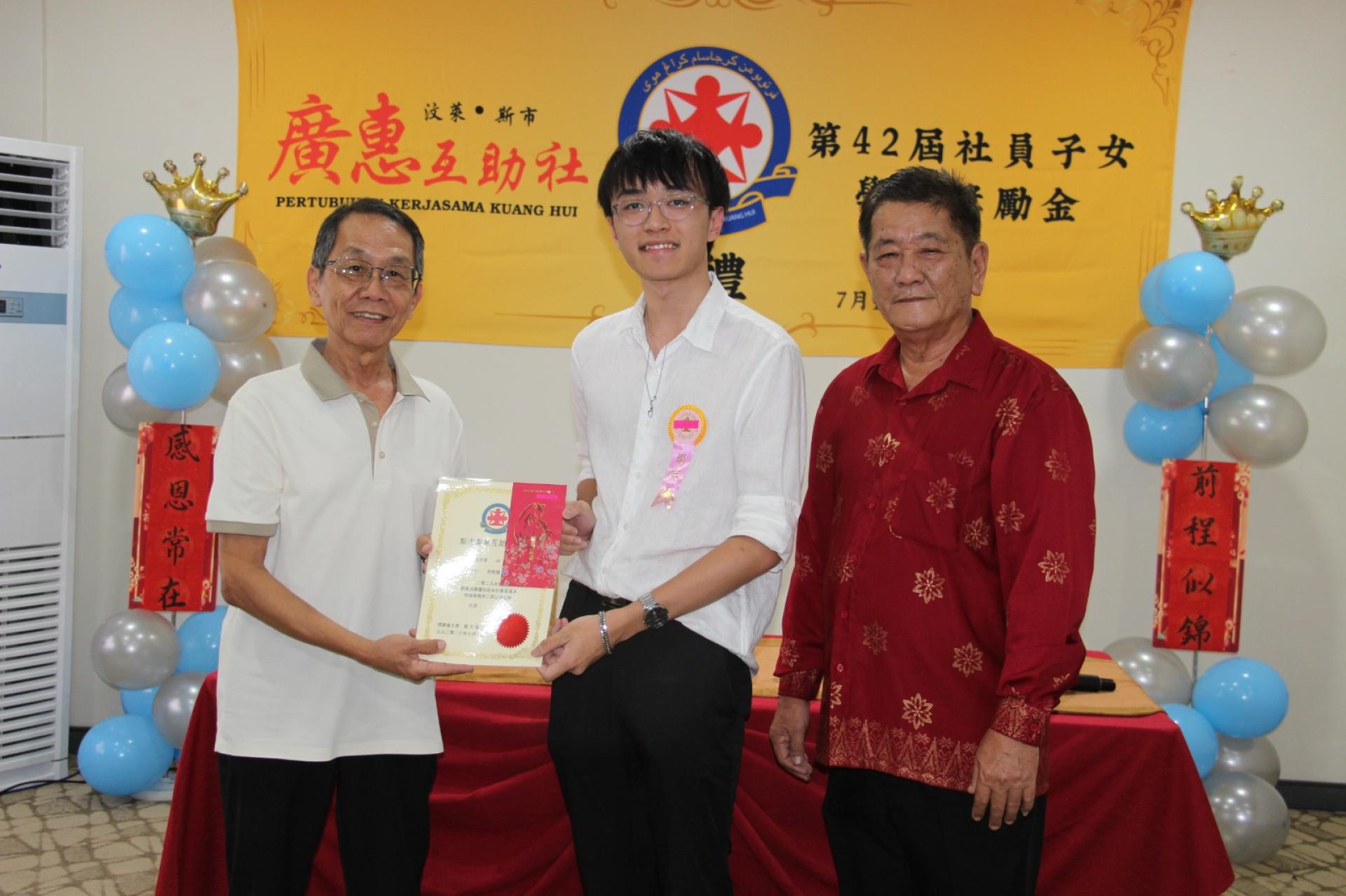 斯市广惠互助社会务顾问邱瑞干（左）颁奖予在汶莱剑桥G.C.E.“A”水平考试中考获2A*2A优异成绩的周程国。右为斯市广惠互助社主席叶天福。