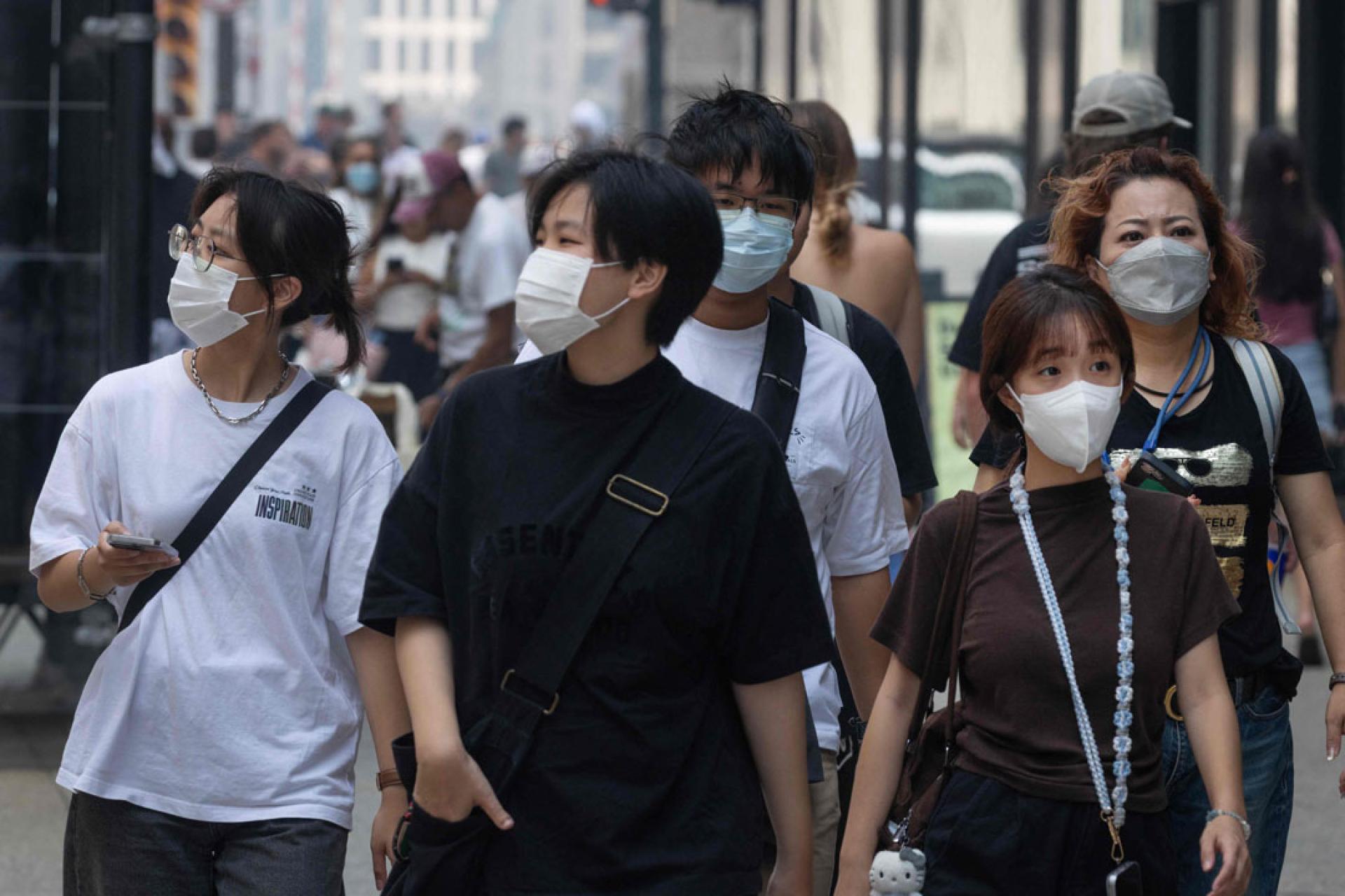 在芝加哥，随着加拿大野火产生的烟雾笼罩城市，人们戴上口罩保护自己。