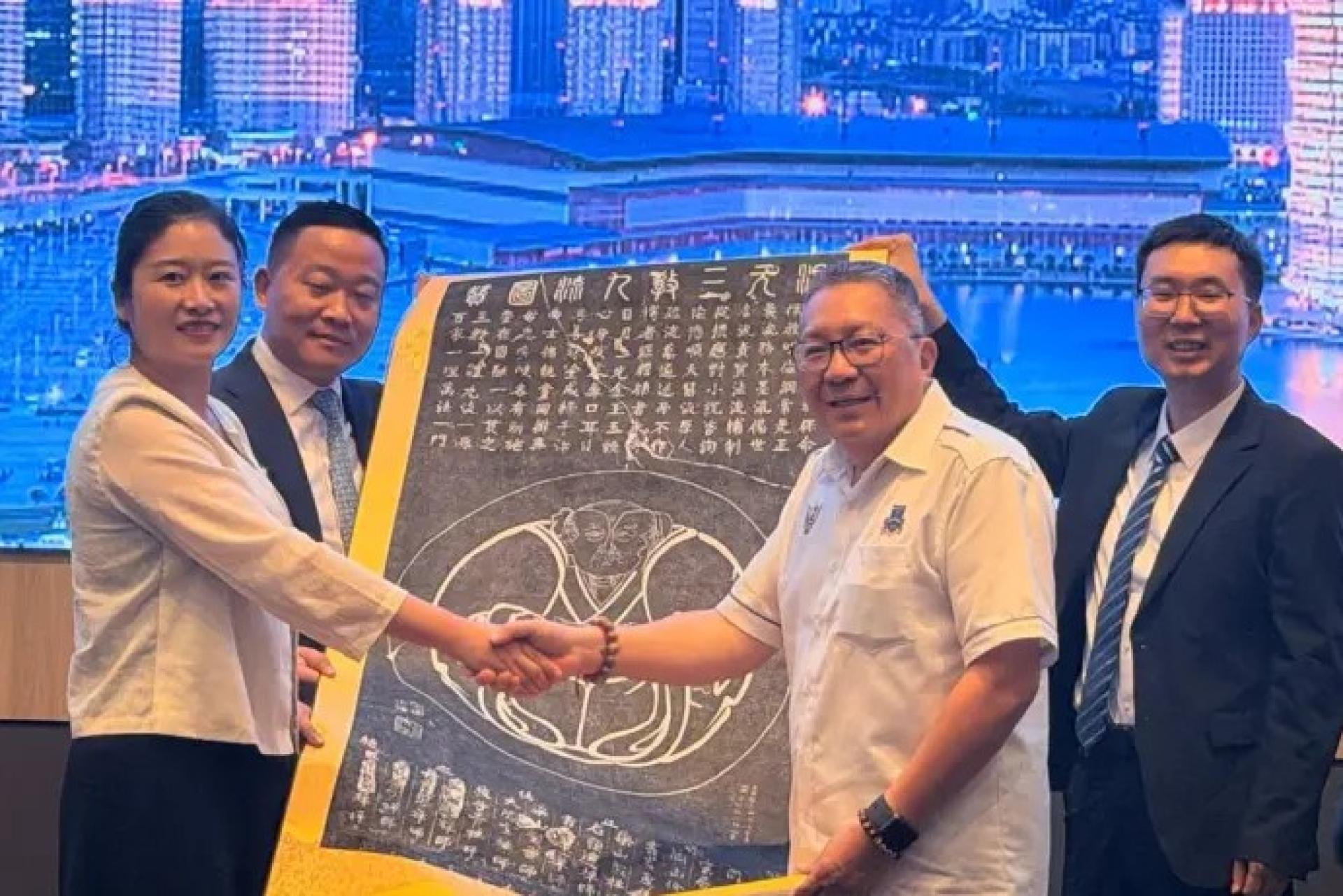 魏玮（左）于2026年8月2日在古晋南市市政局办公室赠送纪念品时与黄鸿圣握手。